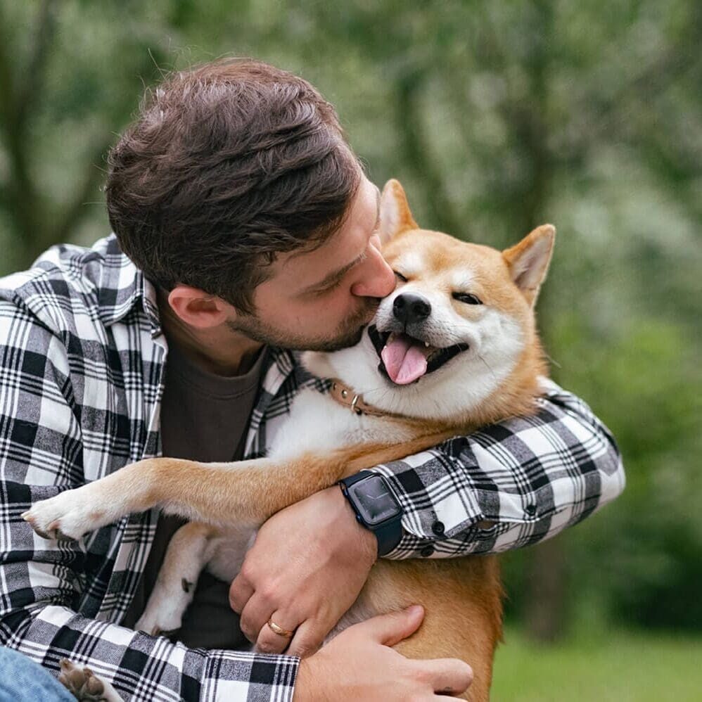 man in plaid shirt kissing his tan dog