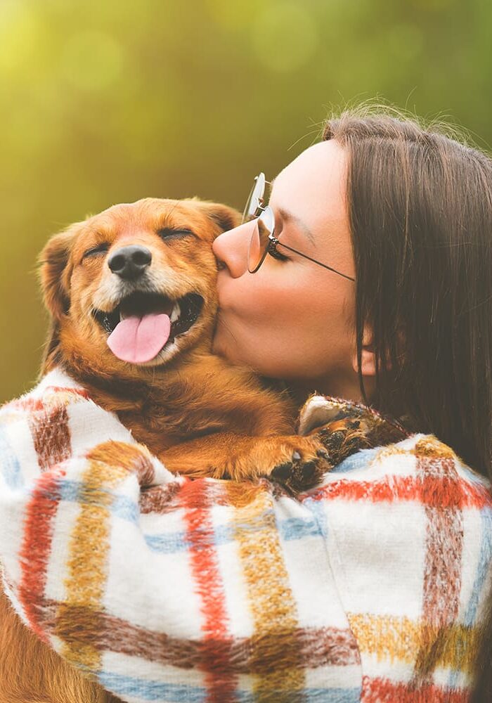 Woman Kissing Brown Dog Outside